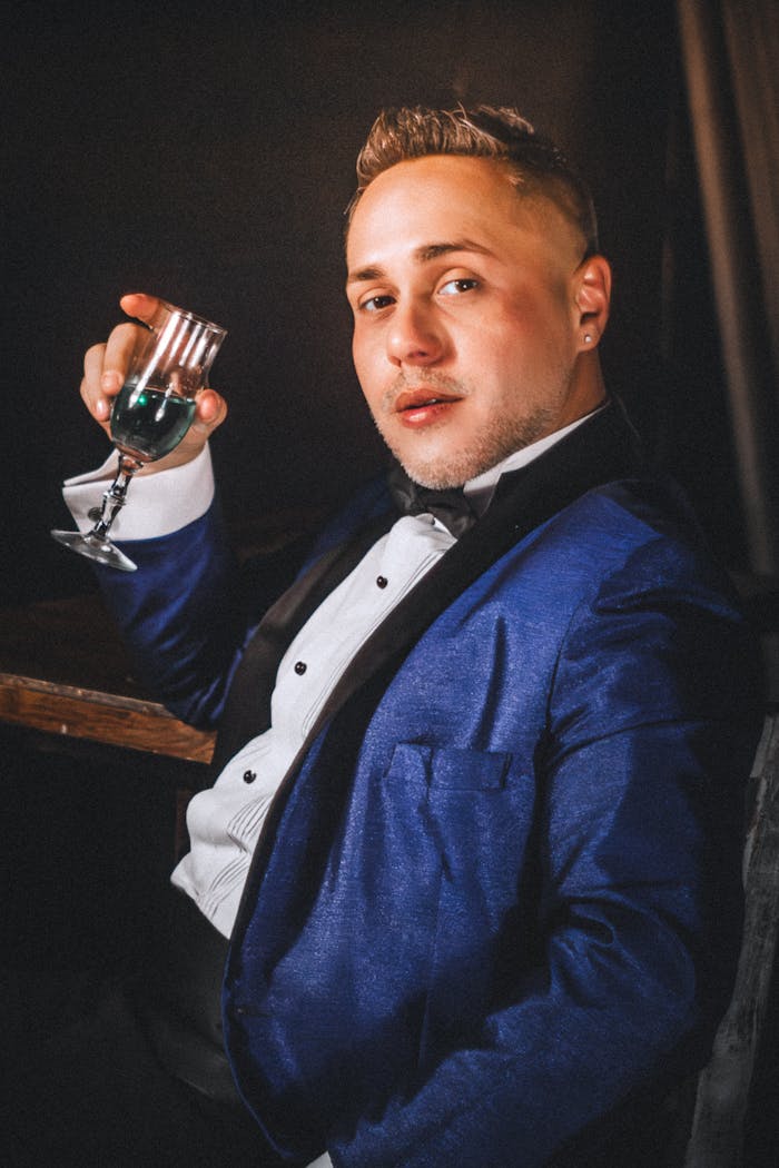 Stylish man in a blue suit enjoying a glass of champagne in an elegant setting.